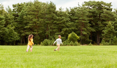 childhood, leisure and people concept - children playing tag game and running at park