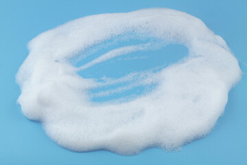 White foam bubbles on blue background. Washing and health care concept.	
