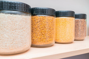 Buckwheat millet, bulgur and rice are in glass containers. Banks of cereals are on a shelf in the closet. food stock.