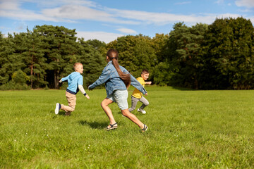 Fototapeta premium childhood, leisure and people concept - group of happy kids playing tag game and running at park