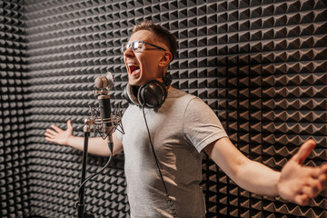The vocalist sings in the studio in a microphone. Man in headphones writes a podcast, an audiobook....