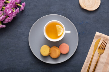 Smile with macaroons and petals on a plate on a dark stone table with flowers. Beautiful delicious dessert