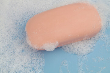 Soap bar and white foam on blue background	
