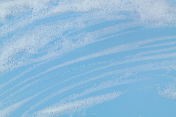 White foam on blue background. Washing and health care concept.	