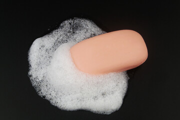 Pink soap with foam bubbles on black background.	