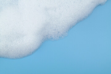 Soap foam bubbles on blue background with room for text.