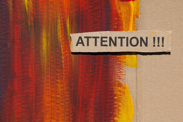 Brown cardboard partially painted in shades of yellow, red and black. On top of it lies a cut out...