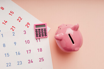 Calculator with calendar and piggy bank on pink background, tax, afinancial goal, money saving...