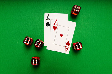 Playing cards with aces and red dice on a green table, casino concept.