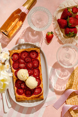 delicious strawberry quick and simple tart pie with vanilla ice cream on the pink background. summer girls brunch party with strawberry pie and champagne. top view sunny light.