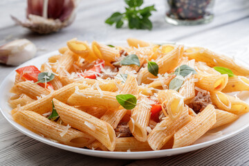 Baked pasta with meat, tomatoes, basil leaves and red pepper