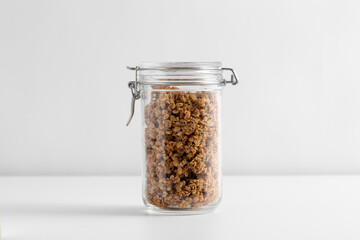 food, healthy eating and diet concept - jar with granola or muesli on white background