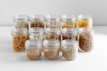 food, culinary and storage concept - jars with different cereals, pasta, beans and cookies on white background