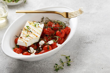 Baked feta pasta. Baked cherry tomatoes and Feta cheese with oil and thyme in white dish. Diet dinner idea.