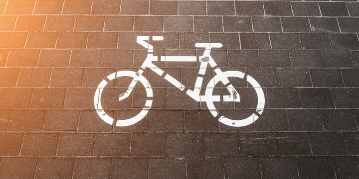 Bike symbol painted with whitewash on tiled road at city street. Bicycle sign on bikeway closeup.