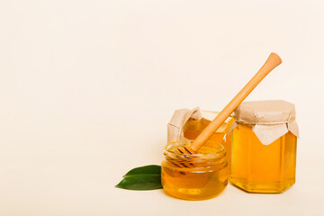 Honey in jar with leaves and honey dipper on colored background top view with copy text