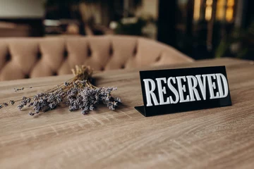 Foto op Aluminium Restaurant reserved table sign standing on wooden table © Igor