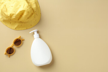 Suntan lotion, baby sunglasses, panama hat on beige background. Kids summer vacation concept. Flat lay, top view.