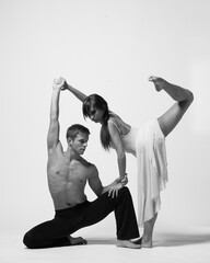 young couple of modern ballet dancers posing on clear studio background