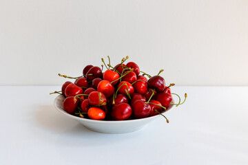 A bowl of sweet cherries on a white table