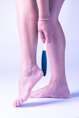 legs of a woman doing with hands treatment on the calluses of the feet on white isolated background in vertical shot