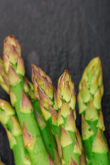 Fresh green asparagus on black table, close up. Selective focus