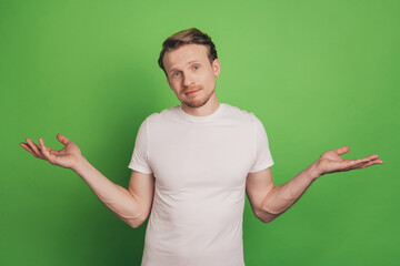 Clueless uncertain ignorant man shrug shoulders isolated on green color background