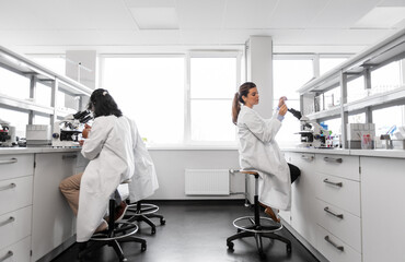 Fototapeta premium science research, work and people concept - international group of scientists with microscopes working in laboratory