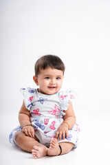 Indian baby girl sitting on white background.