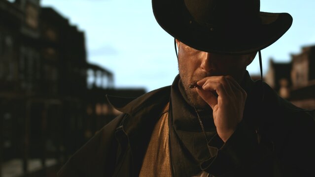 Portrait of cowboy smoking a cigar, old wild west city in the background. Spaghetti, macaroni western style cinematic footage