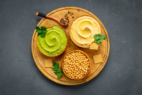 Flatlay of hummus with snacks and herbs. Vegan food background