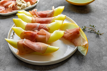 Gourmet snack of honeydew melon and prosciutto ham.