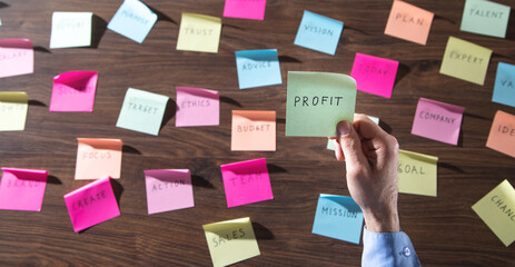 Businessman showing Profit word in sticky note. Working in office