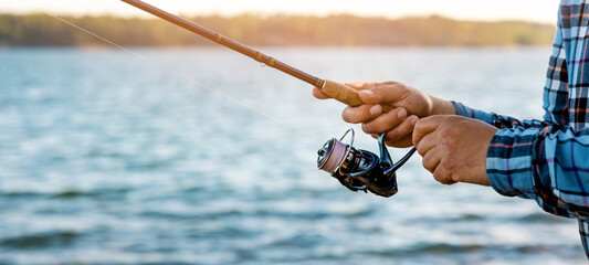 angler retrieve fishing reel line closeup. banner with copy space
