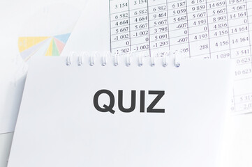 QUIZ text on a notebook on a table next to reports and diagrams, business concept
