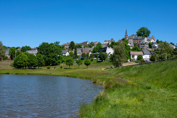Fototapeta na wymiar Le petite ville pittoresque de la Tour-d'Auvergne dans le département du Puy-de-Dôme au printemps au bord d'un lac