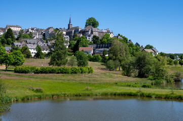 Fototapeta na wymiar Le petite ville pittoresque de la Tour-d'Auvergne dans le département du Puy-de-Dôme au printemps au bord d'un lac