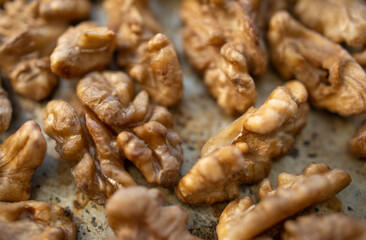 Roasted walnut lies on a metal baking sheet. Protein, healthy nuts, shortage of walnuts, more expensive snacks.