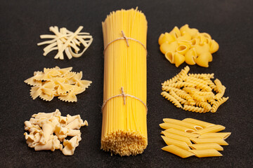 Spaghetti with variety of types and shapes of Italian pasta on black background. Top view