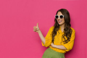 Happy young woman in sunglasses is showing thumb up. - 511021172