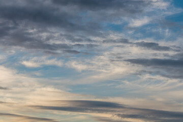 clouds formation across a winter sky with soft pastel sunset tones and different shapes of clouds