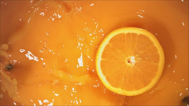 Orange Fruit falling on juice with splash and divided in half.