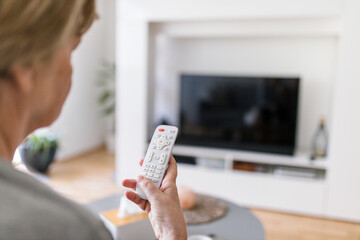 Senior woman with remote control watching tv
