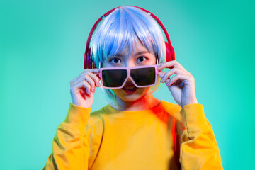 asian girl in yellow sweatshirt with red headphone wearing fashion oversize sunglasses on the green screen background cyberpunk girl concept.