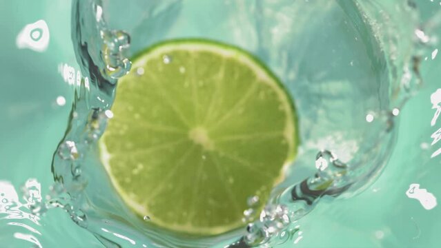 Super slow motion of falling half lime into splashing water. Filmed on high speed cinema camera