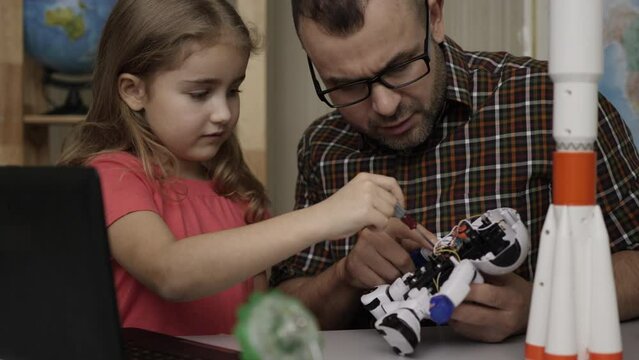 Education Science, Technology Children, Programming Electronic Robotics School Lesson. Girl Schoolgirl And Teacher Assembling Robots in Modern Classroom. Dad and Daughter Assemble Robot at Home.