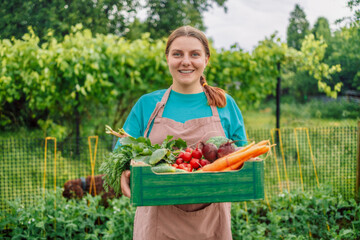 Pretty woman withgreen paper box of vegetables in her garden on countryside field. Vegetables harvest freshly picked from garden healthy lifestyle vegan food organic