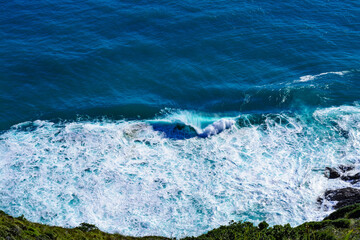 Aerial view of a giant ocean wave crushing onto the shore. Top down photo of turquoise sea water surface. White foam waves texture as natural background