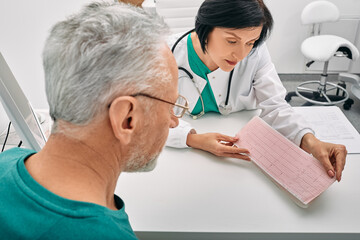 Experienced doctor consulting senior man on results of cardiogram and test. Diagnostic heart...