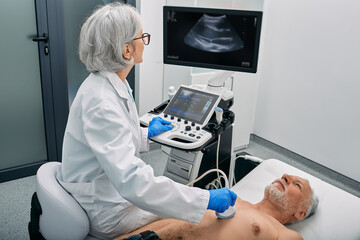 Heart ultrasound exam for senior man with ultrasound specialist while medical exam at hospital - 511029194